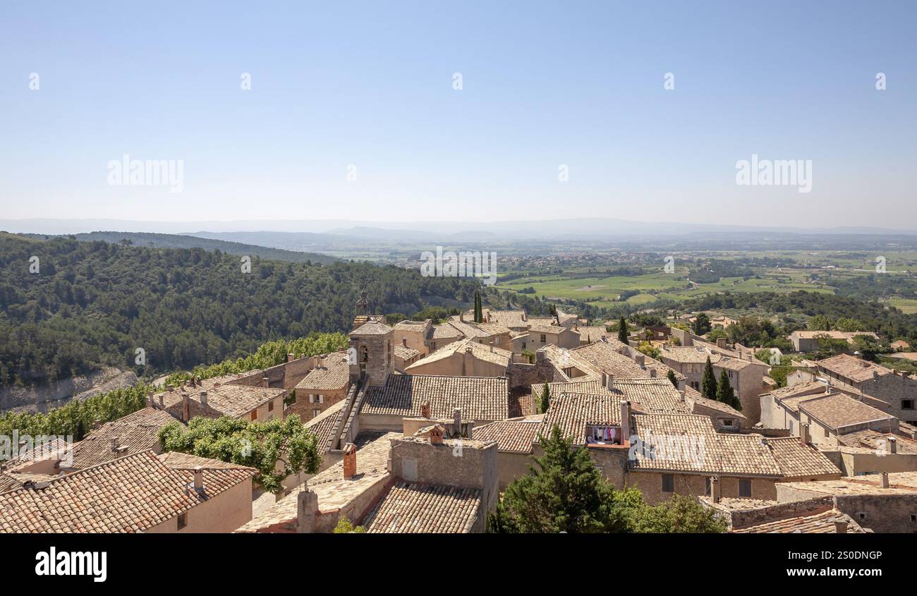 Vista panoramica su un pittoresco villaggio con tetti in terracotta incorniciati dalla verde campagna, le Barroux, Provenza, Francia, Europa Foto Stock