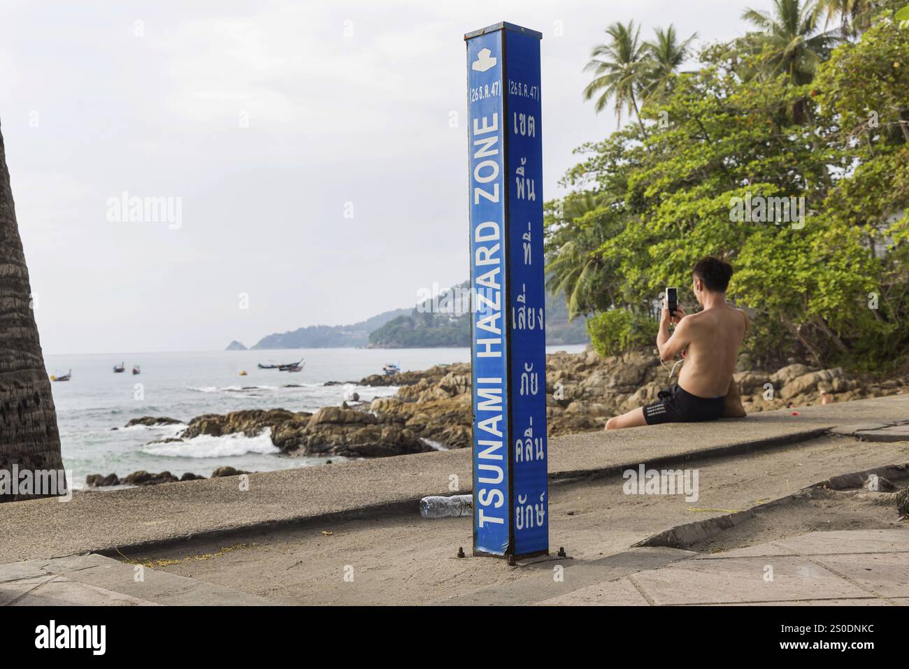 Zona di pericolo per lo tsunami. Cartello segnaletico, indicazione delle vie di fuga in caso di un altro terremoto. Area della spiaggia e strada costiera nella città di Patong, K. Foto Stock