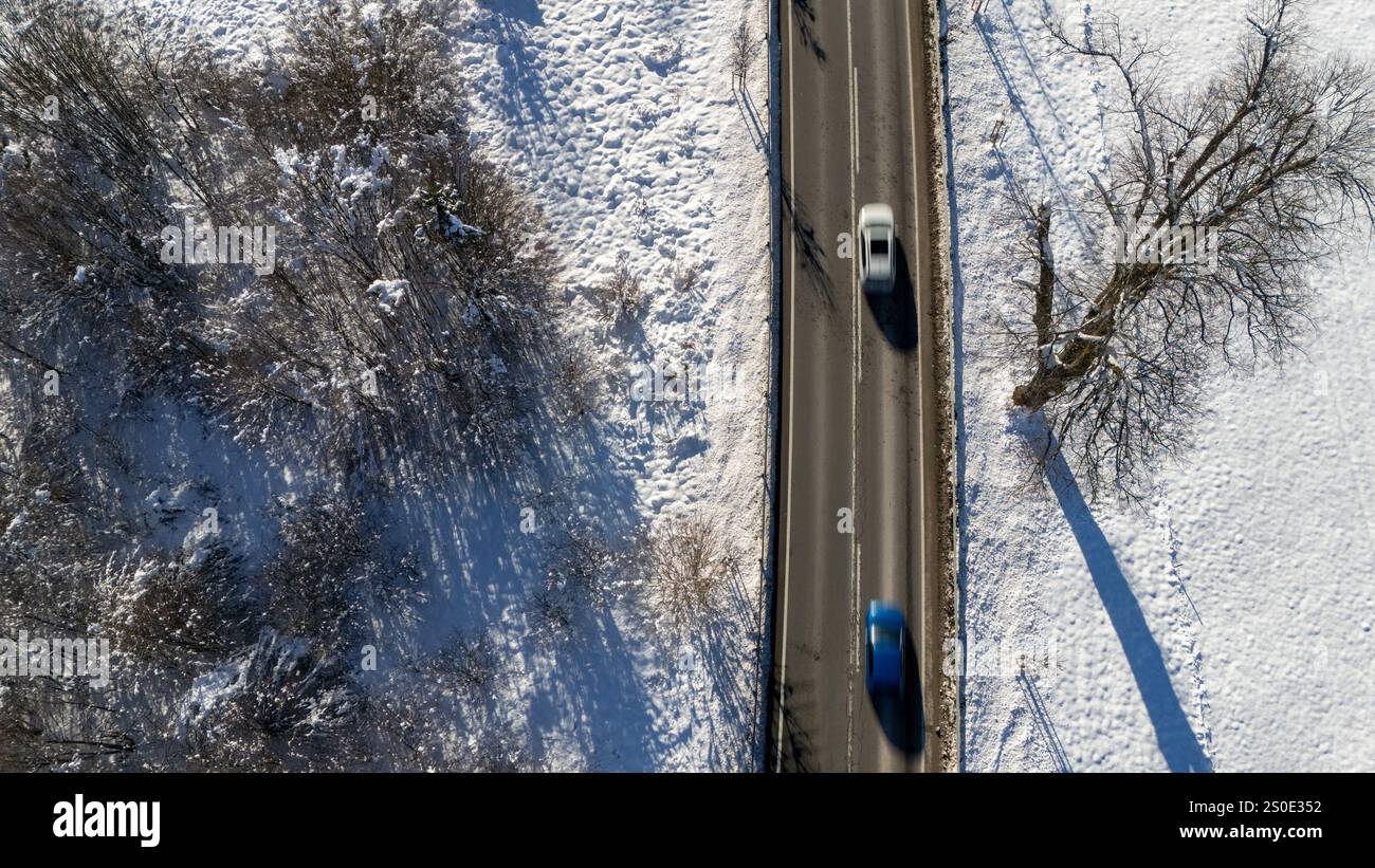 Veduta aerea delle auto che guidano su una strada rurale innevata Foto Stock