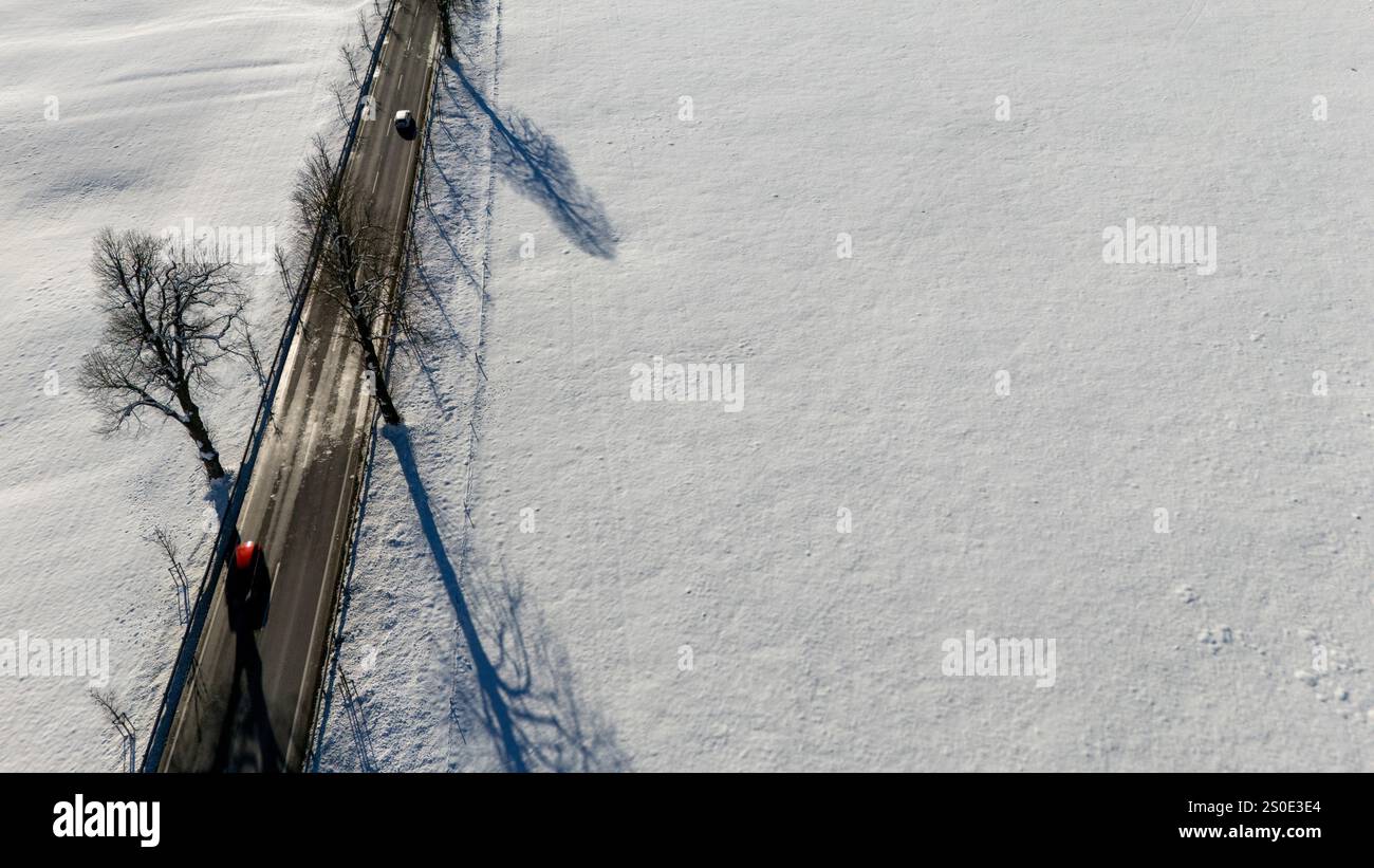 Ripresa aerea ad alto angolo di una strada rurale che attraversa un vasto paesaggio innevato. Foto Stock