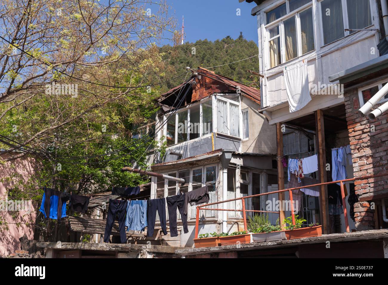 Vista sulla vecchia via Tbilisi con balconi di case povere in una giornata di sole Foto Stock