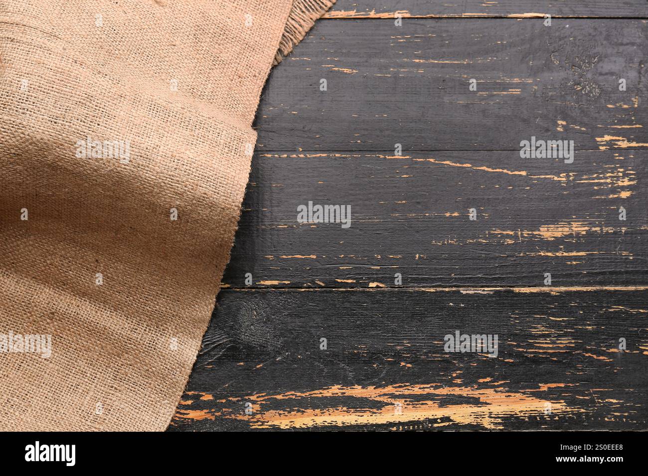Pezzo di tessuto burlap su sfondo in legno nero Foto Stock