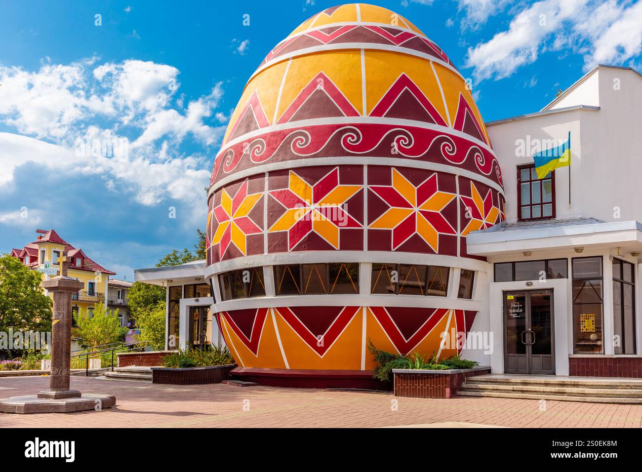 Un grande e colorato edificio a forma di uovo con un design rosso e giallo. L'edificio e' circondato da un cortile con una fontana nel centro Foto Stock