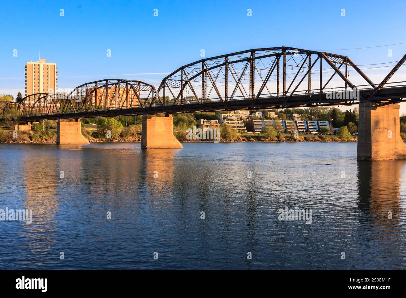 Un ponte attraversa un fiume con una città sullo sfondo. Il ponte è vecchio e ha un aspetto rustico Foto Stock