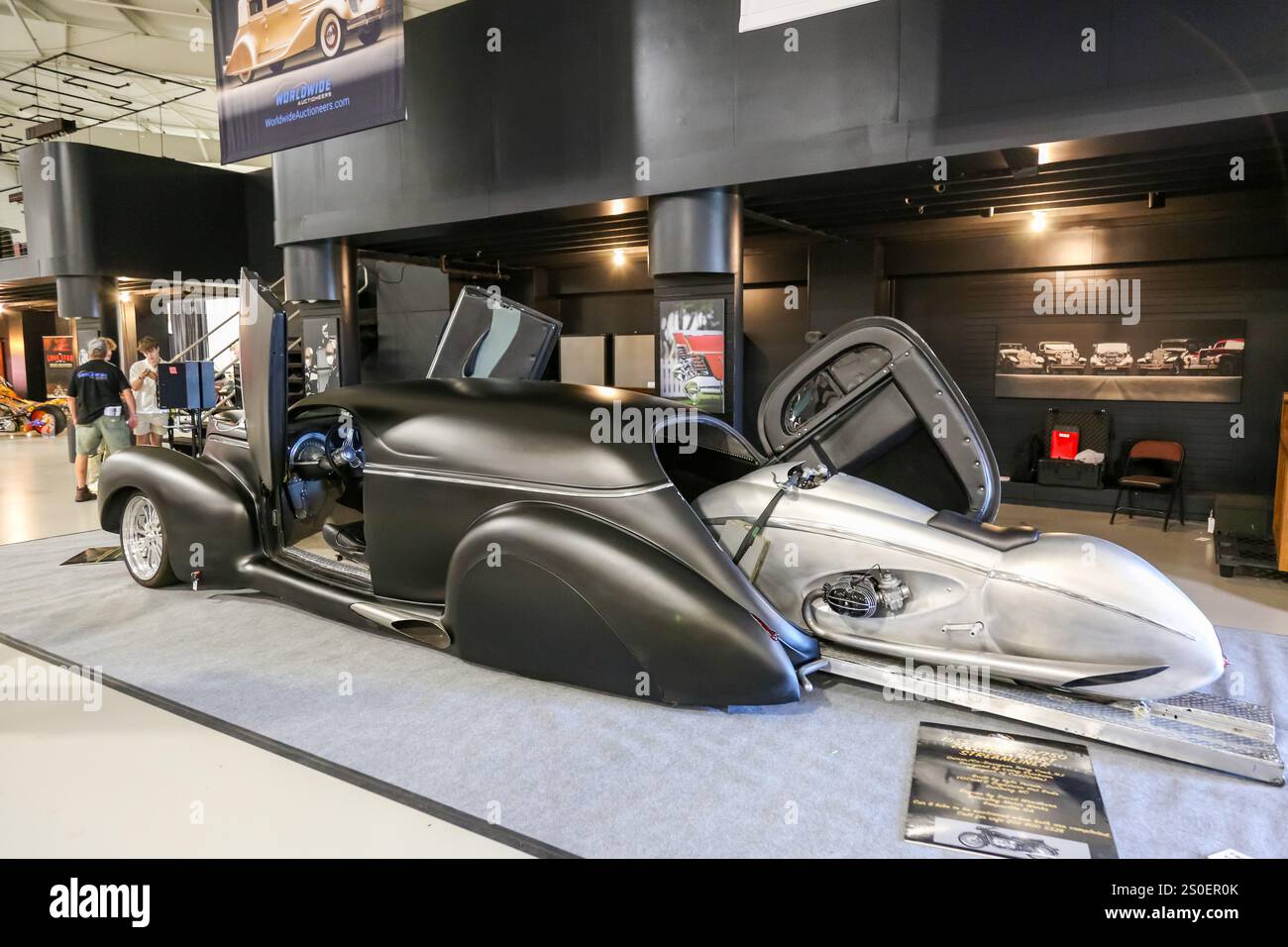 Una Lincoln Zephyr berlina nera del 1941 altamente personalizzata con una moto BMW R69 del 1955 dal design essenziale presso gli spettatori del Worldwide Auctioneers di Auburn, Indiana. Foto Stock