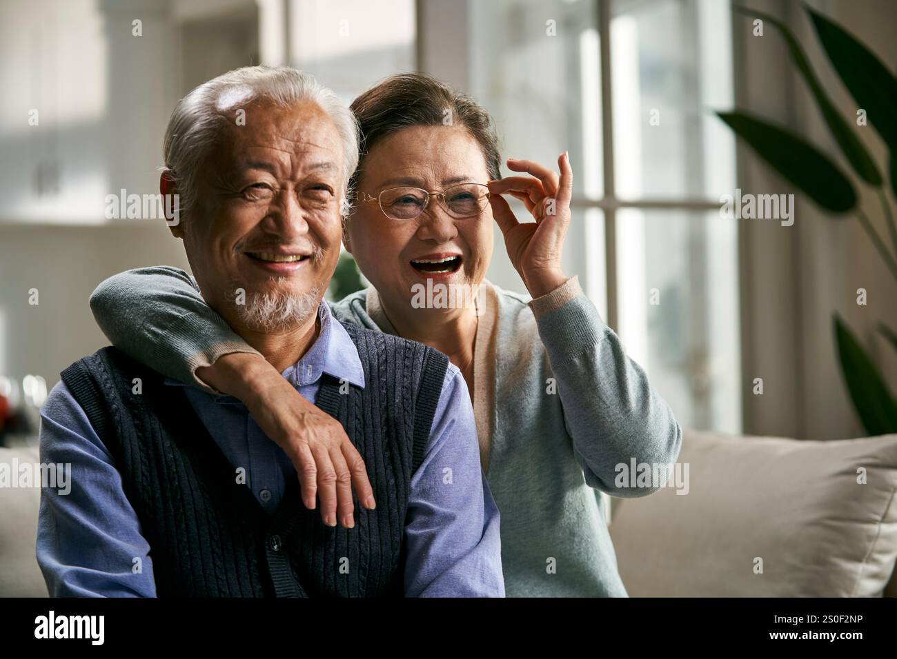 ritratto di una felice coppia asiatica anziana seduta sul divano guardando la macchina fotografica sorridente Foto Stock