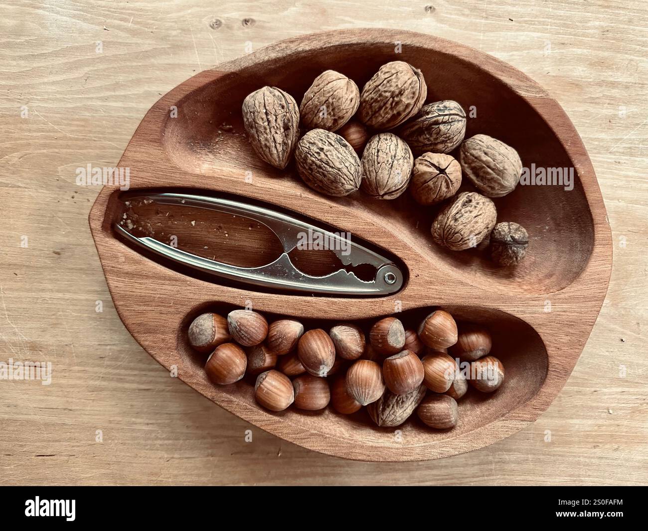 Una ciotola a forma di parte interna di una noce ripiena di noci e nocciole Foto Stock