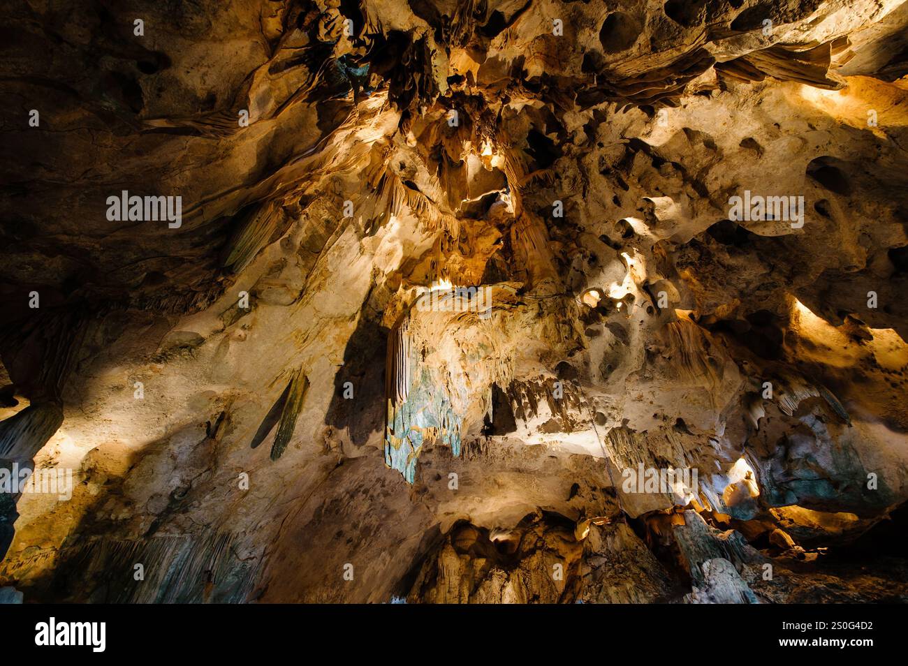 una grotta con stalagmiti e stalattiti. La grotta è grande e scura e le pareti sono coperte da una varietà di formazioni rocciose diverse. Lo stalagmi Foto Stock