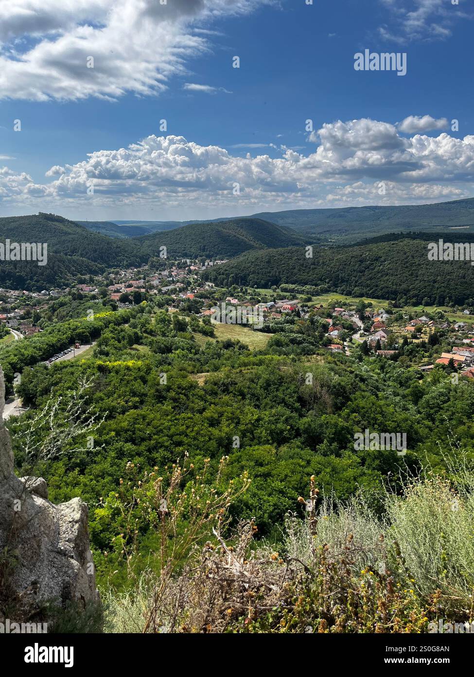 L'immagine mostra un paesaggio panoramico con una vista da un punto panoramico elevato. Il primo piano comprende un terreno roccioso e una vegetazione secca. - Immagine stock catturata con smartphone