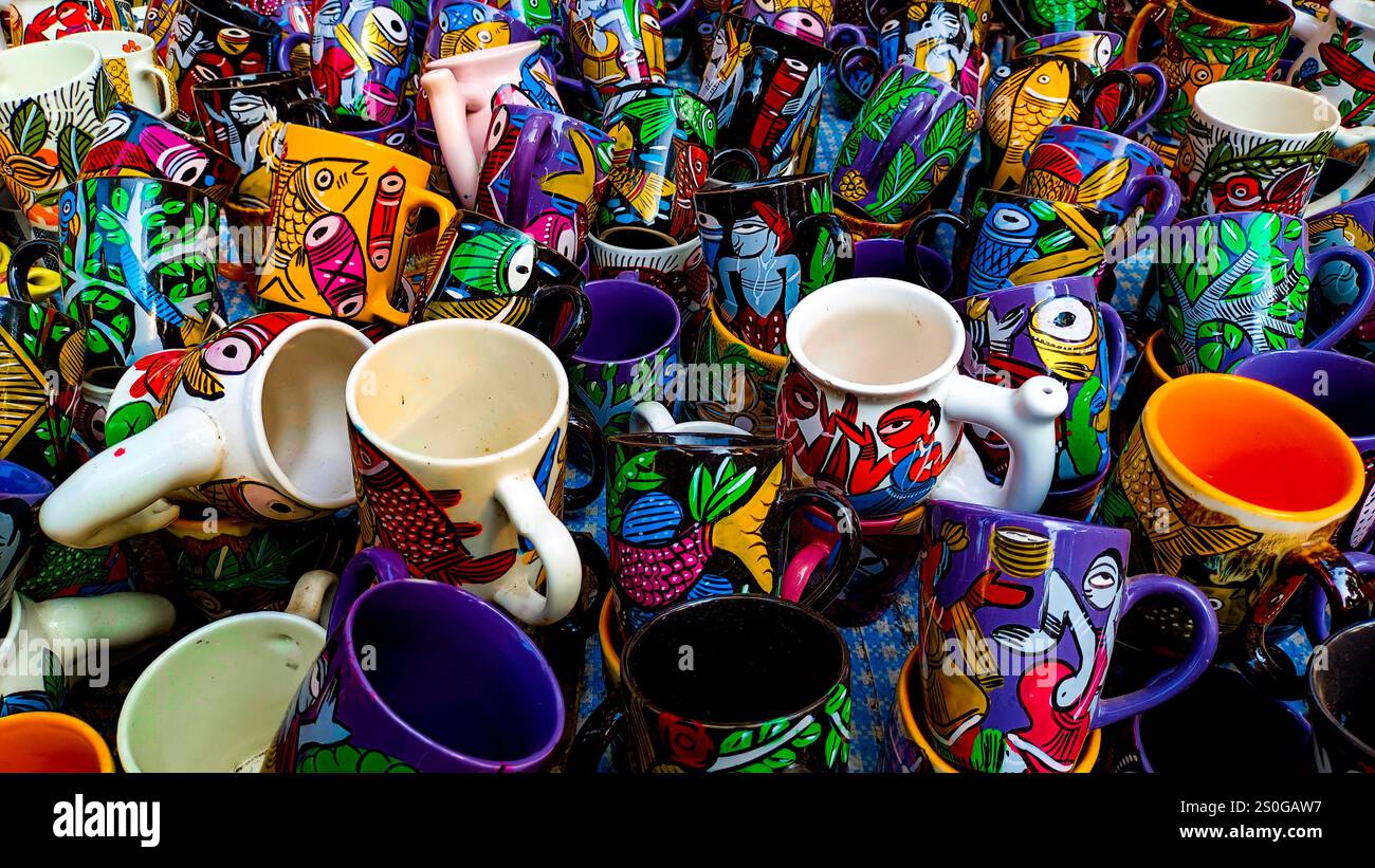 tazze e tazze da caffè in ceramica dipinte a mano da artigiani rurali dei villaggi indiani. Le tazze hanno colori vivaci e motivi intricati Foto Stock