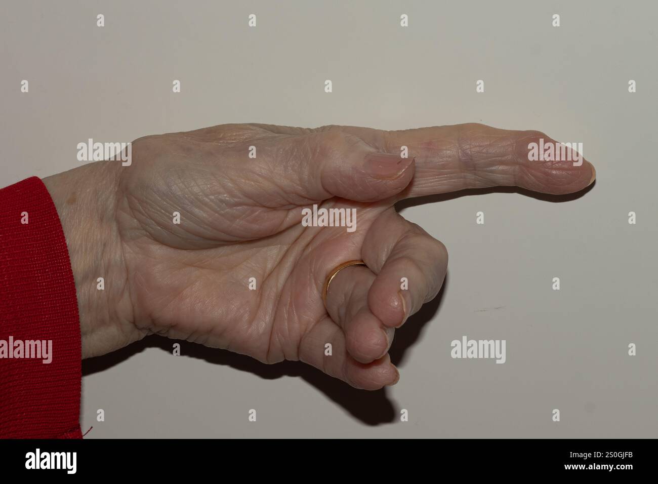 Vista dettagliata della mano di una donna anziana estesa in avanti, con particolare attenzione alla pelle e alle unghie testurizzate, che illustrano i segni naturali dell'invecchiamento su una Foto Stock