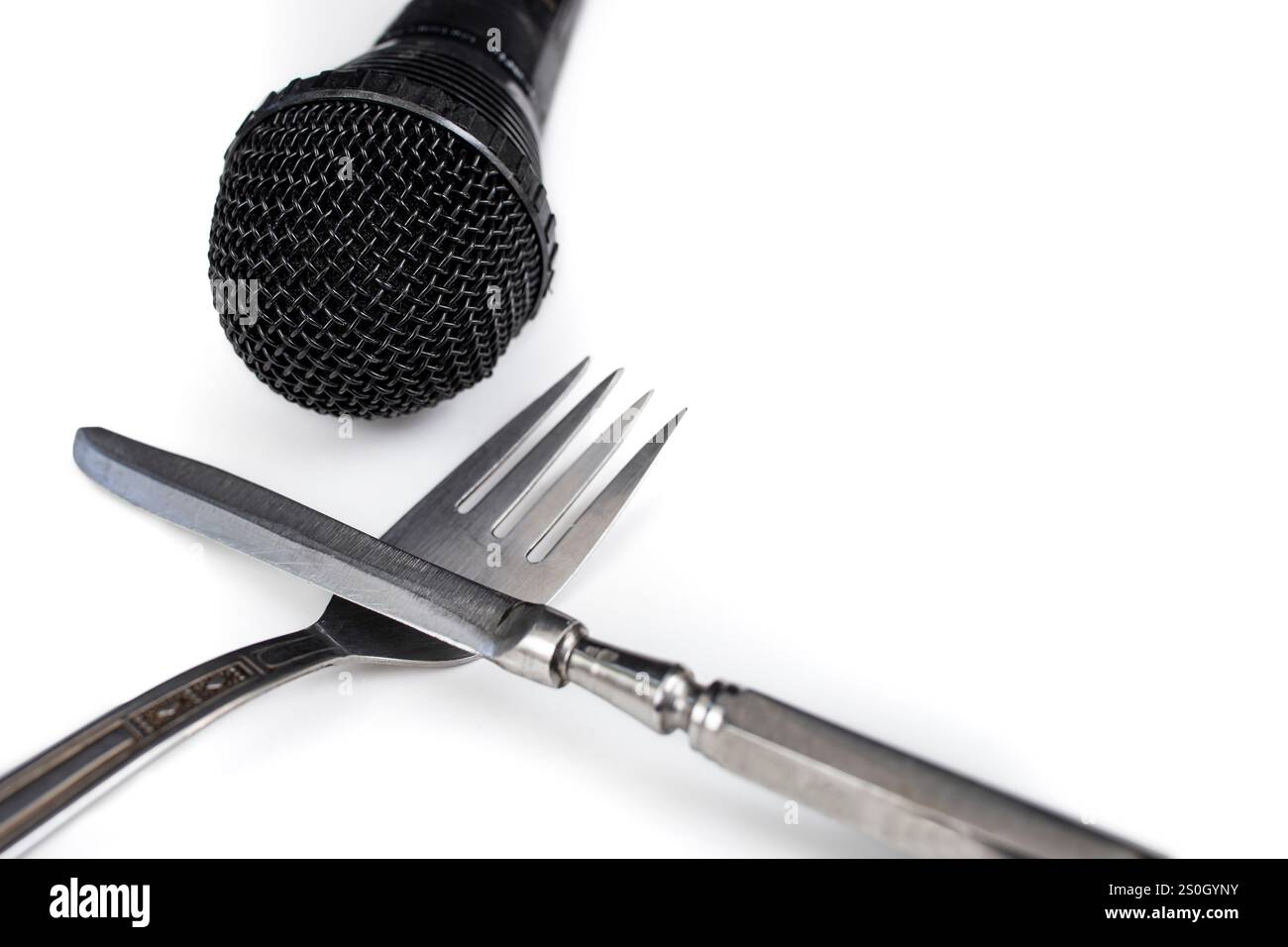 Microfono nero accanto a forchetta e coltello su un piatto bianco, concetto di blog culinario Foto Stock