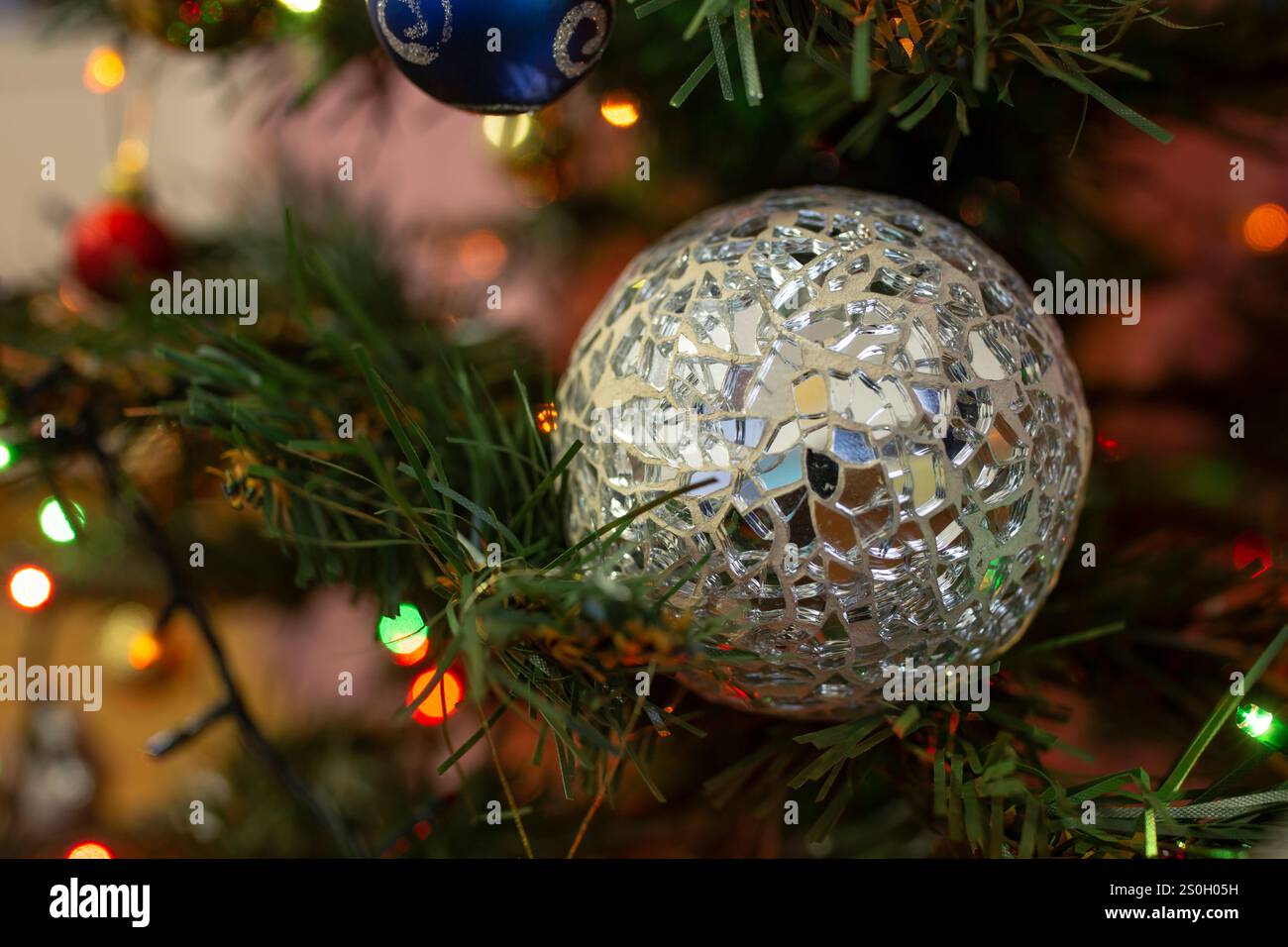 Design unico di una palla da discoteca con frammenti di specchio irregolari su cemento, in un albero di natale in plastica, texture astratta Foto Stock