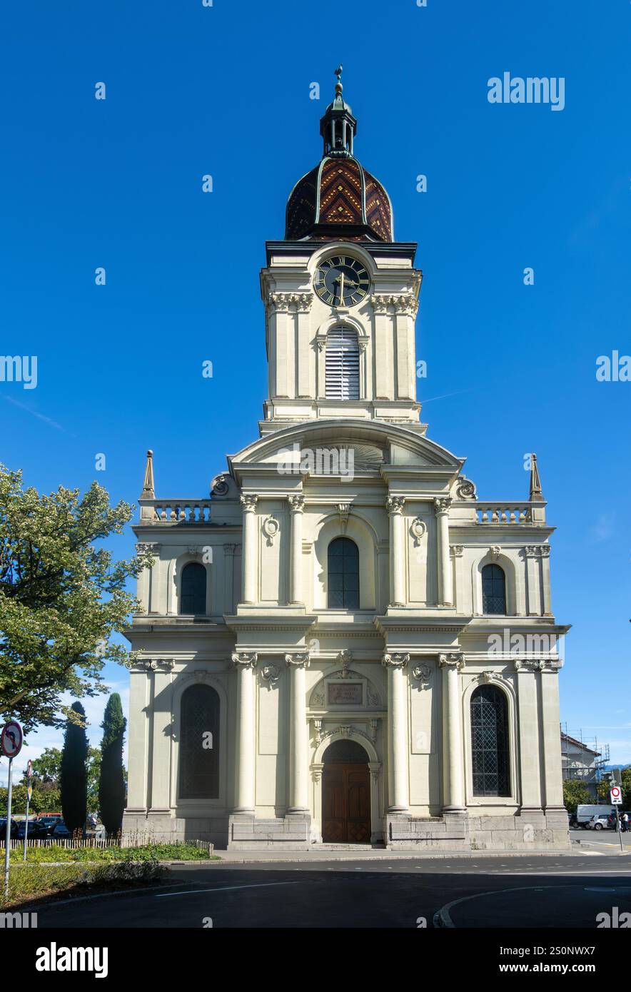 Una chiesa protestante riformata a Morges, Svizzera, caratterizzata da un'alta torre dell'orologio e architettura classica, si erge sotto un cielo azzurro. Foto Stock