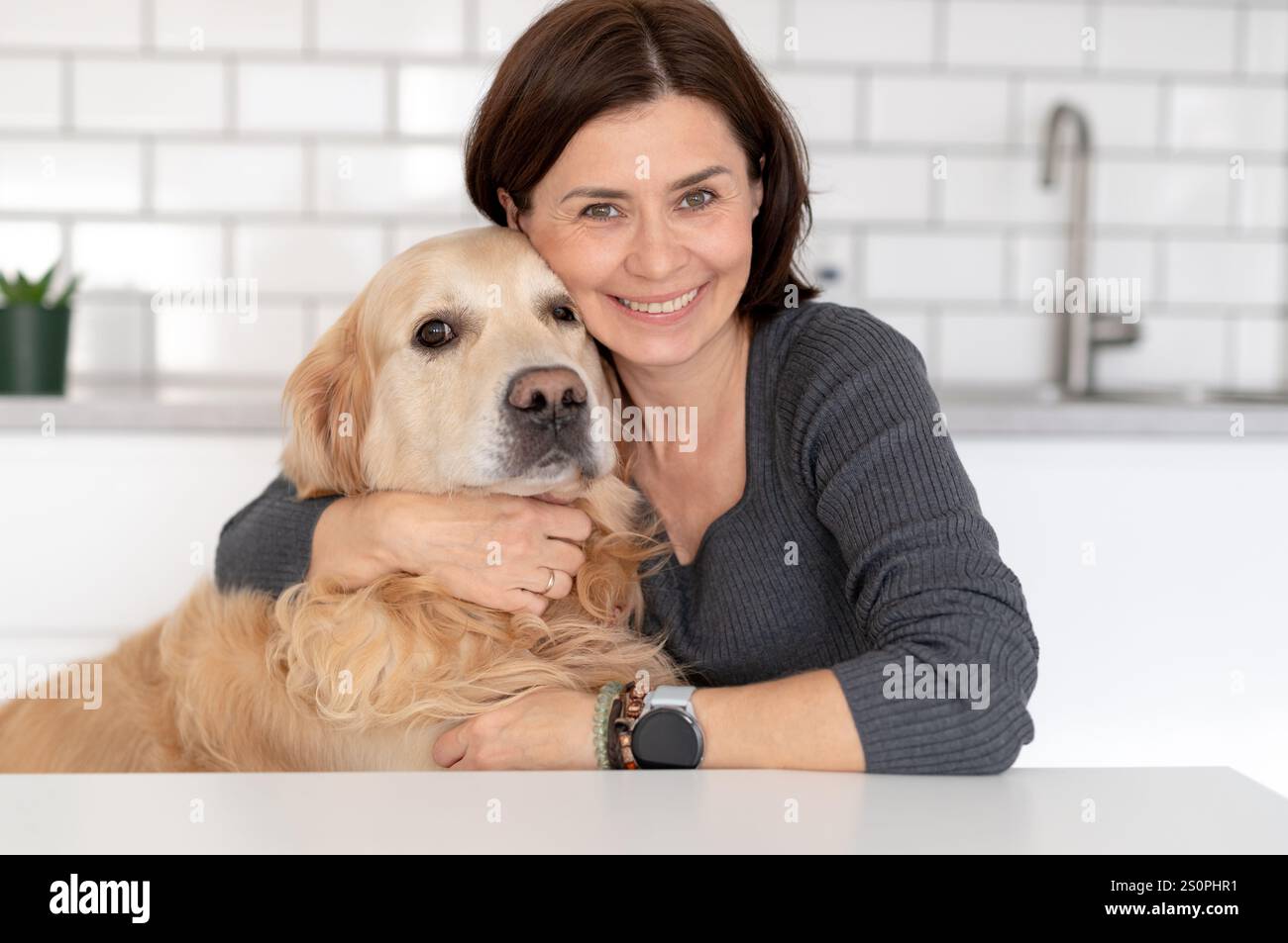 Happy Woman con Golden Retriever Dog Smiles mentre posa per Photo at Home Foto Stock