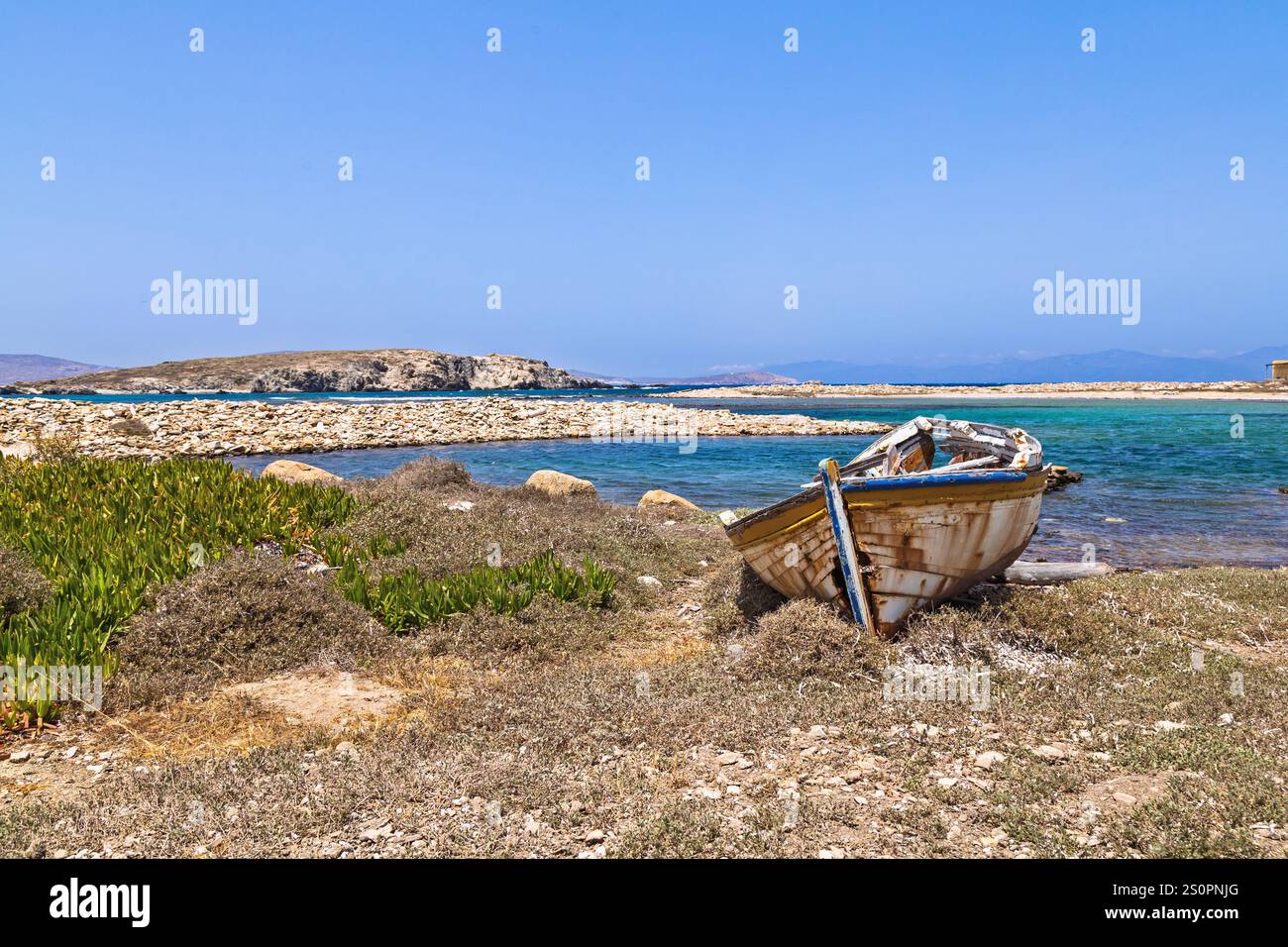 Barca in legno abbandonata su una panoramica costa con acque cristalline, Delo, Grecia Foto Stock