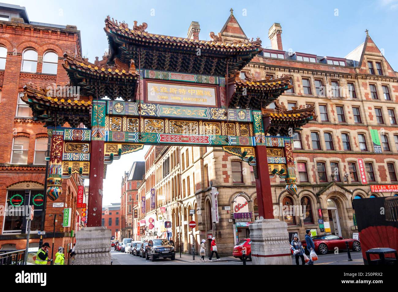 Vivace vista dell'iconico arco di ingresso cinese nella Chinatown di Manchester, circondato da edifici storici e dalla vivace vita cittadina Foto Stock