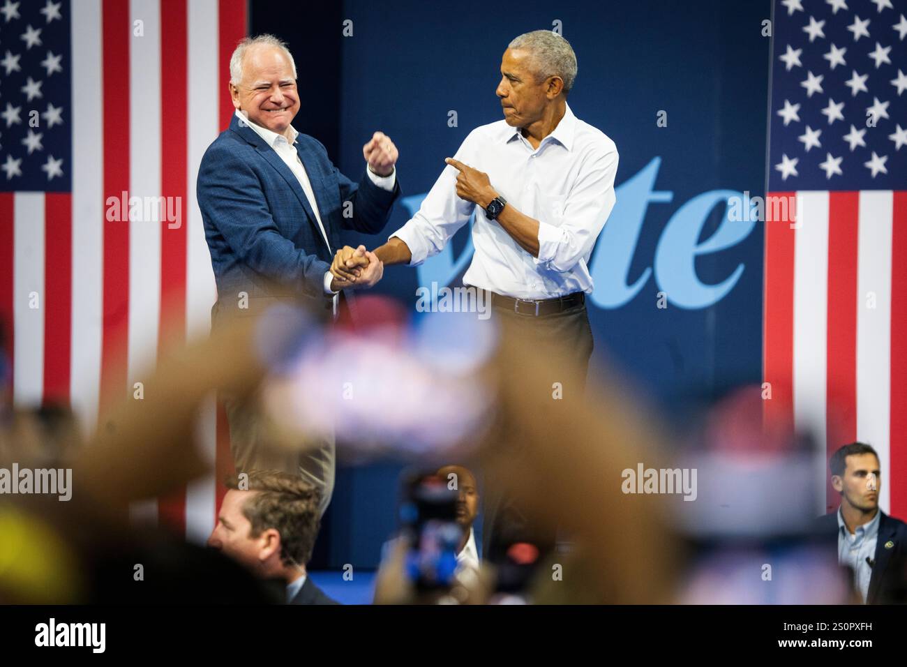 L'ex presidente Barack Obama stringe la mano a Tim Walz, candidato al vp, sul palco di una manifestazione durante la campagna presidenziale del 2024. Foto Stock