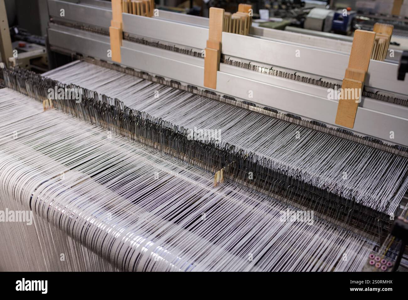 Primo piano della macchina per tessitura. Una macchina per telai per indumenti o etichette tessute. Tessitrice per l'industria dell'abbigliamento. Foto Stock