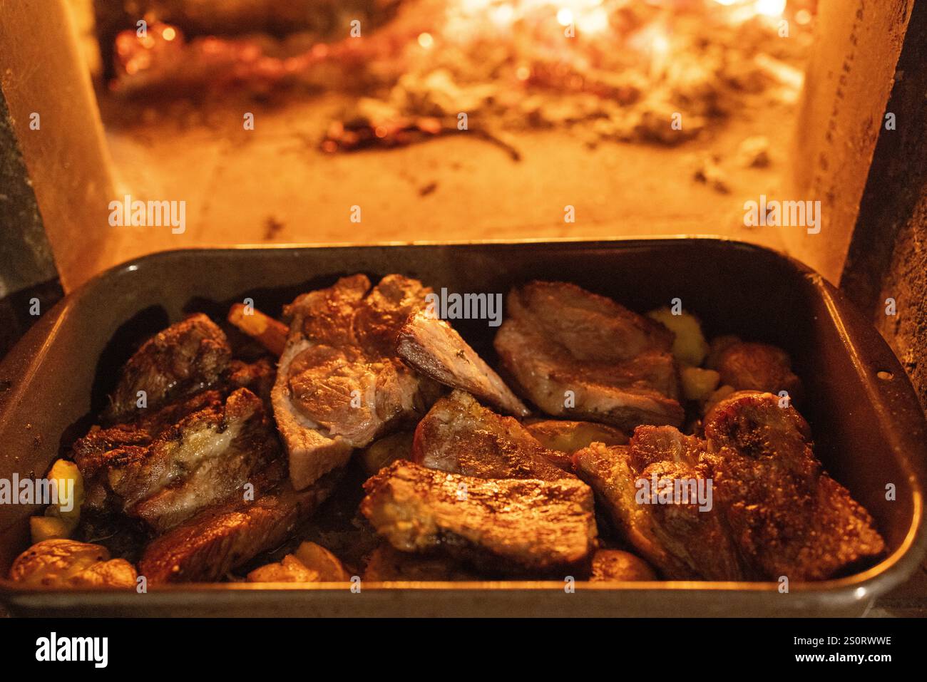 Carne e verdure arrostite in un piatto da forno all'interno di un forno a legna Foto Stock