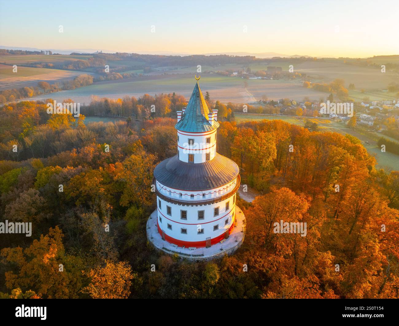 Il castello di caccia barocco Humprecht si trova maestosamente sopra Sobotka, circondato da un vivace fogliame autunnale mentre sorge il sole, che proietta un bagliore dorato sul paesaggio. Foto Stock