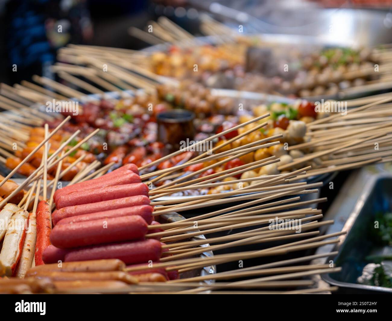 Pentola stufata con polpette e salsicce spiedini in salsa rossa piccante. Cibo di strada asiatico in Thailandia. Foto Stock