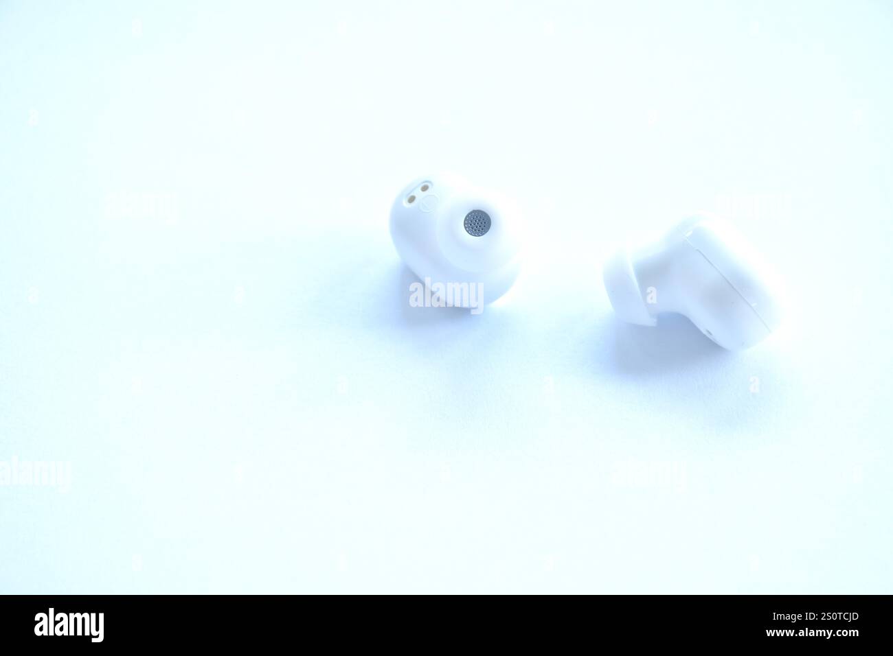 auricolari wireless per il collegamento con il telefono cellulare disposti su sfondo bianco Foto Stock