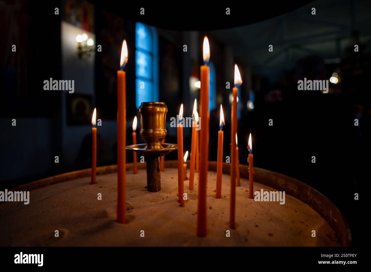 , Deutschland, 28.12.2024, Leuchtende Kerzen in einem Sandhalter, umgeben von Dunkelheit und goldenem Licht, schaffen eine besinnliche, spirituelle A Foto Stock