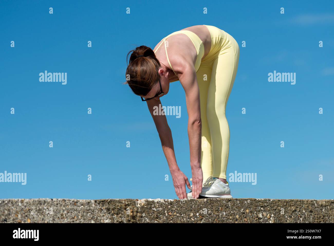 donna sportiva in piedi toccando i piedi, all'aperto Foto Stock