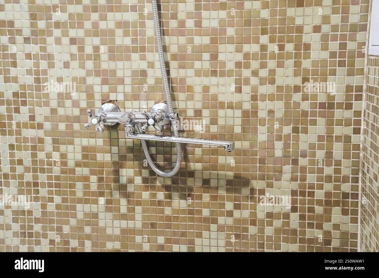 Doccia in primo piano nel bagno sullo sfondo di piastrelle a mosaico beige. Il concetto di stile di vita, ambiente. Foto di alta qualità Foto Stock