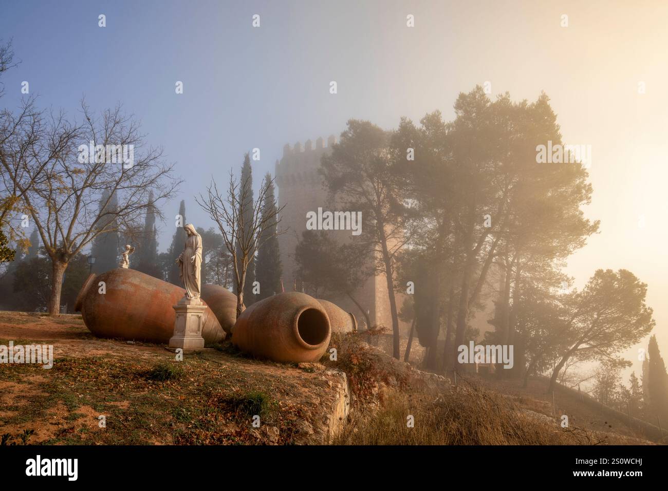Statua della Vergine Maria tra alcuni grandi contenitori in ceramica e, sullo sfondo, il castello di Alarcón, Cuenca, Castilla-la Mancha, Spagna, in un fo Foto Stock