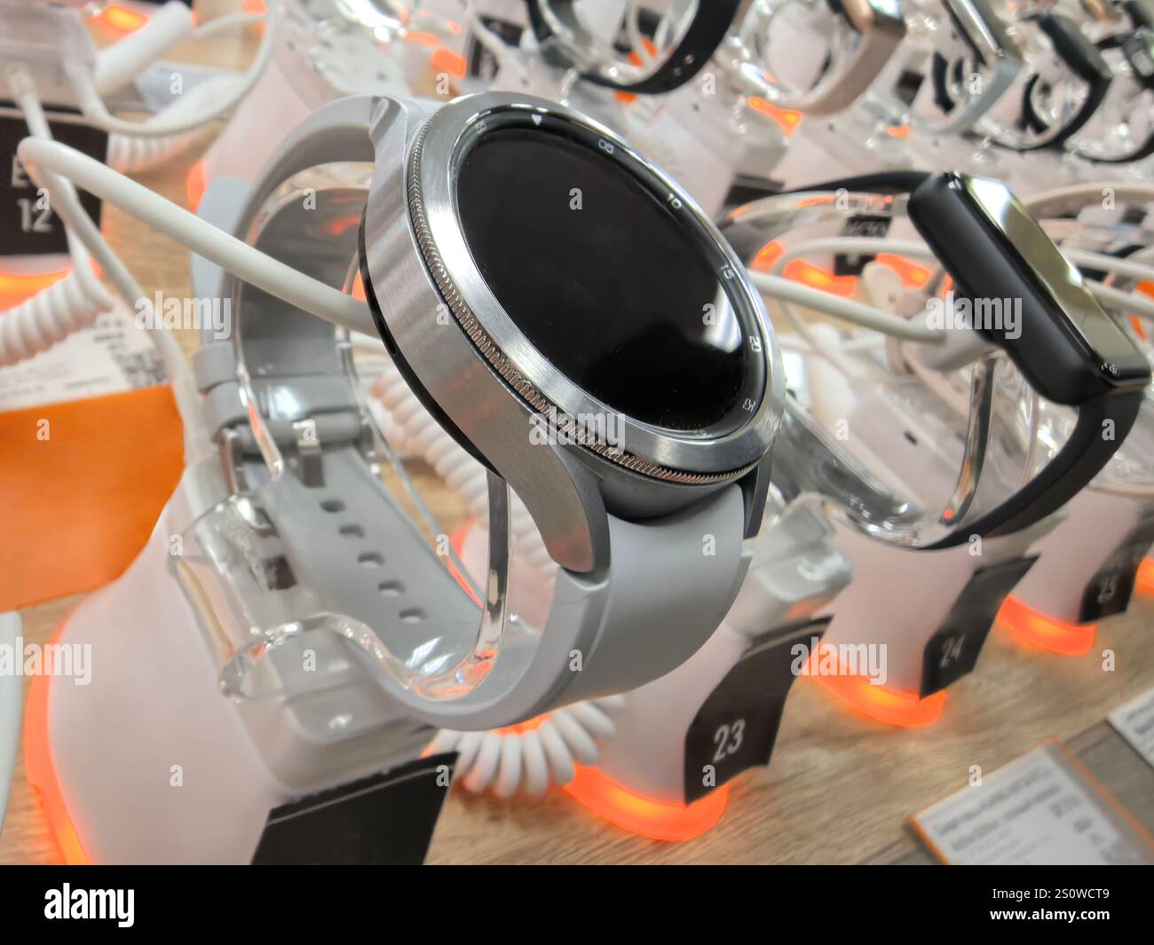 Gli smartwatch luminosi sono caratterizzati da design e funzionalità all'avanguardia, esposti in modo preminente in un ambiente retail. Gli amanti dello shopping entusiasti esplorano le opzioni in mezzo a elega Foto Stock
