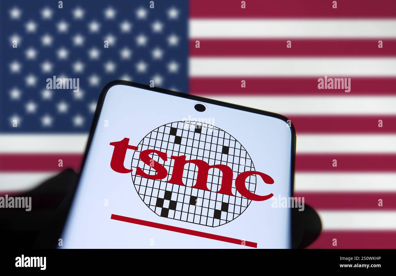Il logo TSMC viene visualizzato sullo smartphone e la bandiera americana sullo sfondo. Foto Stock