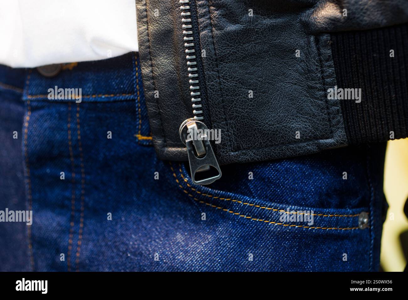 Primo piano di una zip con giacca in pelle nera e jeans blu Foto Stock