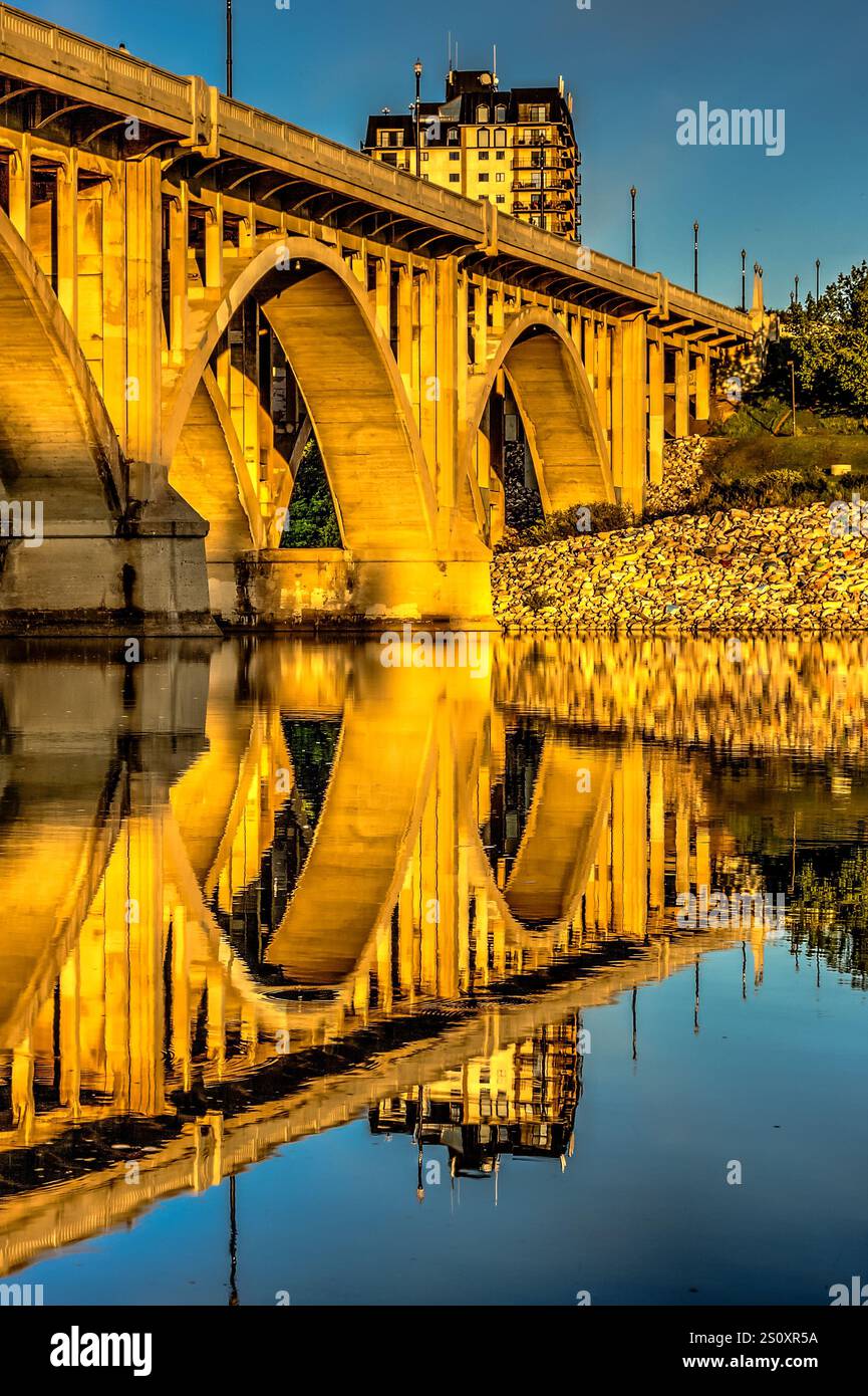 Un ponte con un riflesso del cielo e un edificio nell'acqua. Il ponte è un grande arco e l'acqua è calma Foto Stock