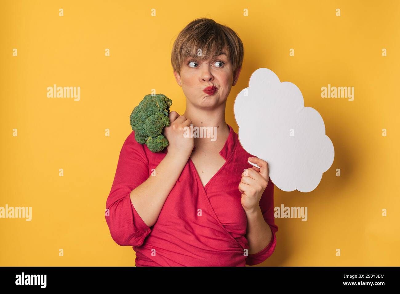 Una foto in studio di una giovane donna con broccoli freschi e una carta intestata vuota. Il concetto di mangiare sano Foto Stock