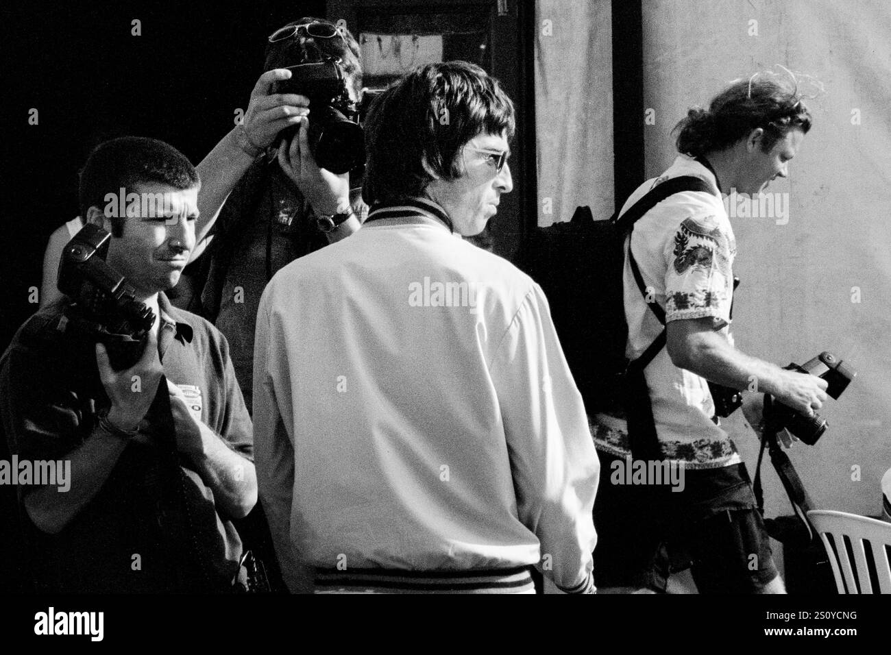 NOEL GALLAGHER, OASIS, PAPARAZZI, BACKSTAGE, READING FESTIVAL, 2000: Noel Gallagher degli Oasis è circondato da paparazzi nel backstage al Reading Festival, Reading, Inghilterra, Regno Unito, il 25 agosto 2000. La band fece da headliner al festival quella sera con il loro quarto album "Standing on the Shoulder of Giants". Foto: Rob Watkins. INFO: Noel Gallagher è un musicista, cantautore e produttore inglese, meglio conosciuto come il chitarrista principale degli Oasis. Famoso per inni come "Wonderwall", in seguito formò gli High Flying Birds di Noel Gallagher, continuando la sua eredità di brillantezza Britpop. Foto Stock