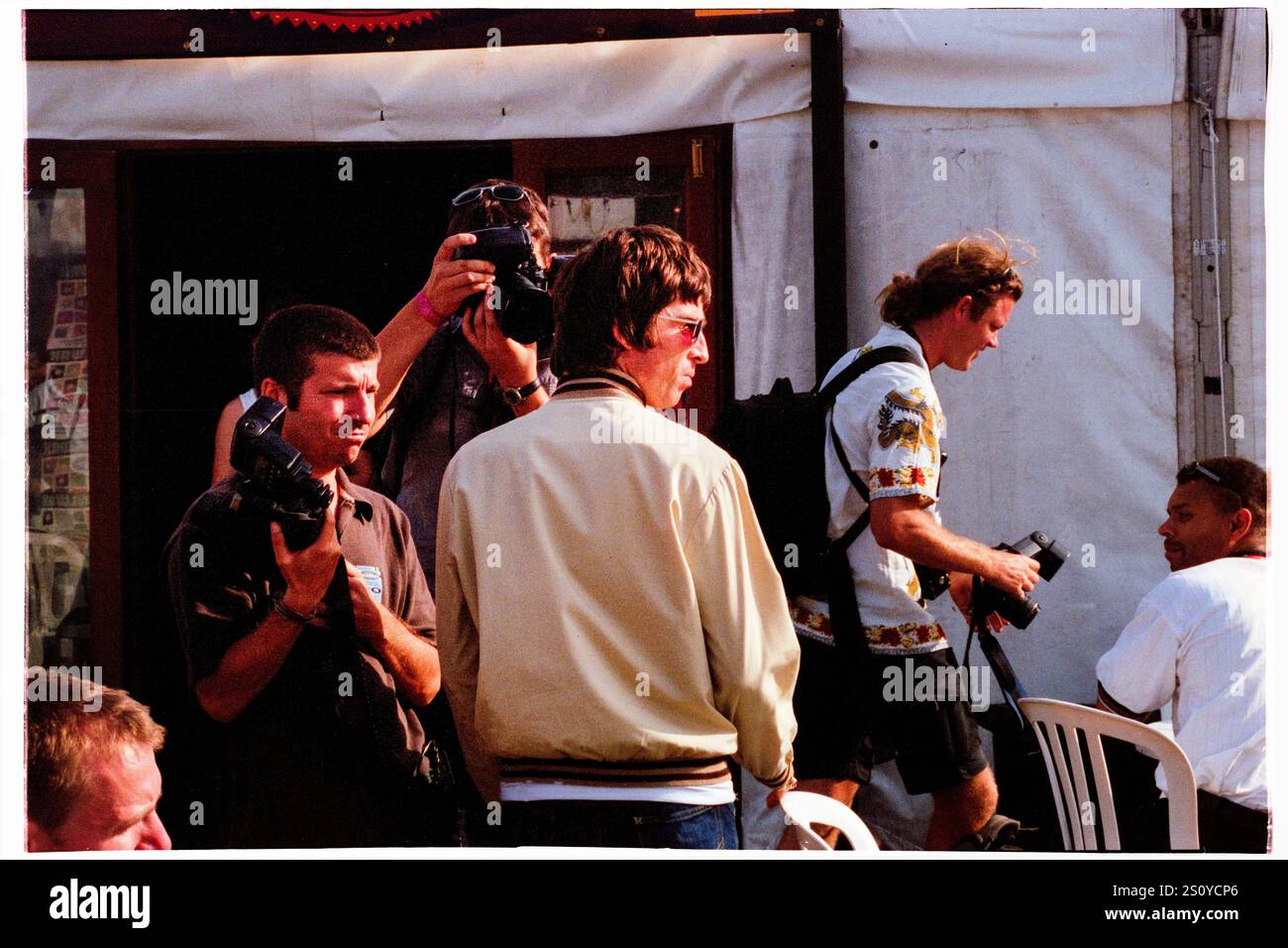 NOEL GALLAGHER, OASIS, PAPARAZZI, BACKSTAGE, READING FESTIVAL, 2000: Noel Gallagher degli Oasis è circondato da paparazzi nel backstage al Reading Festival, Reading, Inghilterra, Regno Unito, il 25 agosto 2000. La band fece da headliner al festival quella sera con il loro quarto album "Standing on the Shoulder of Giants". Foto: Rob Watkins. INFO: Noel Gallagher è un musicista, cantautore e produttore inglese, meglio conosciuto come il chitarrista principale degli Oasis. Famoso per inni come "Wonderwall", in seguito formò gli High Flying Birds di Noel Gallagher, continuando la sua eredità di brillantezza Britpop. Foto Stock