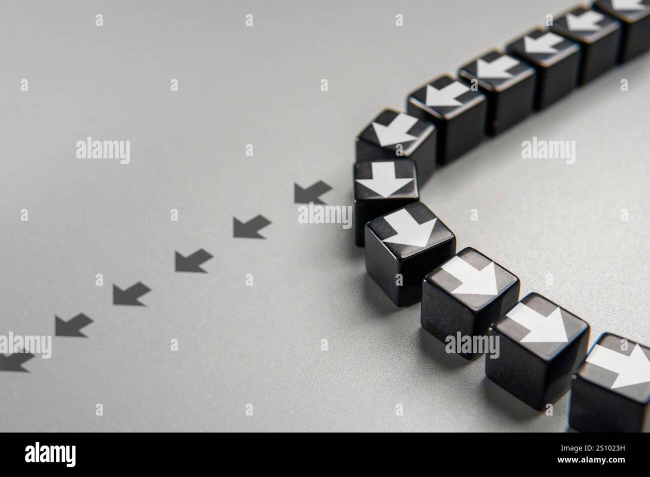 Una fila di cubi neri con frecce bianche che puntano in direzioni diverse. Un cambiamento di rotta o un cambiamento nel concetto di strategia. Foto Stock
