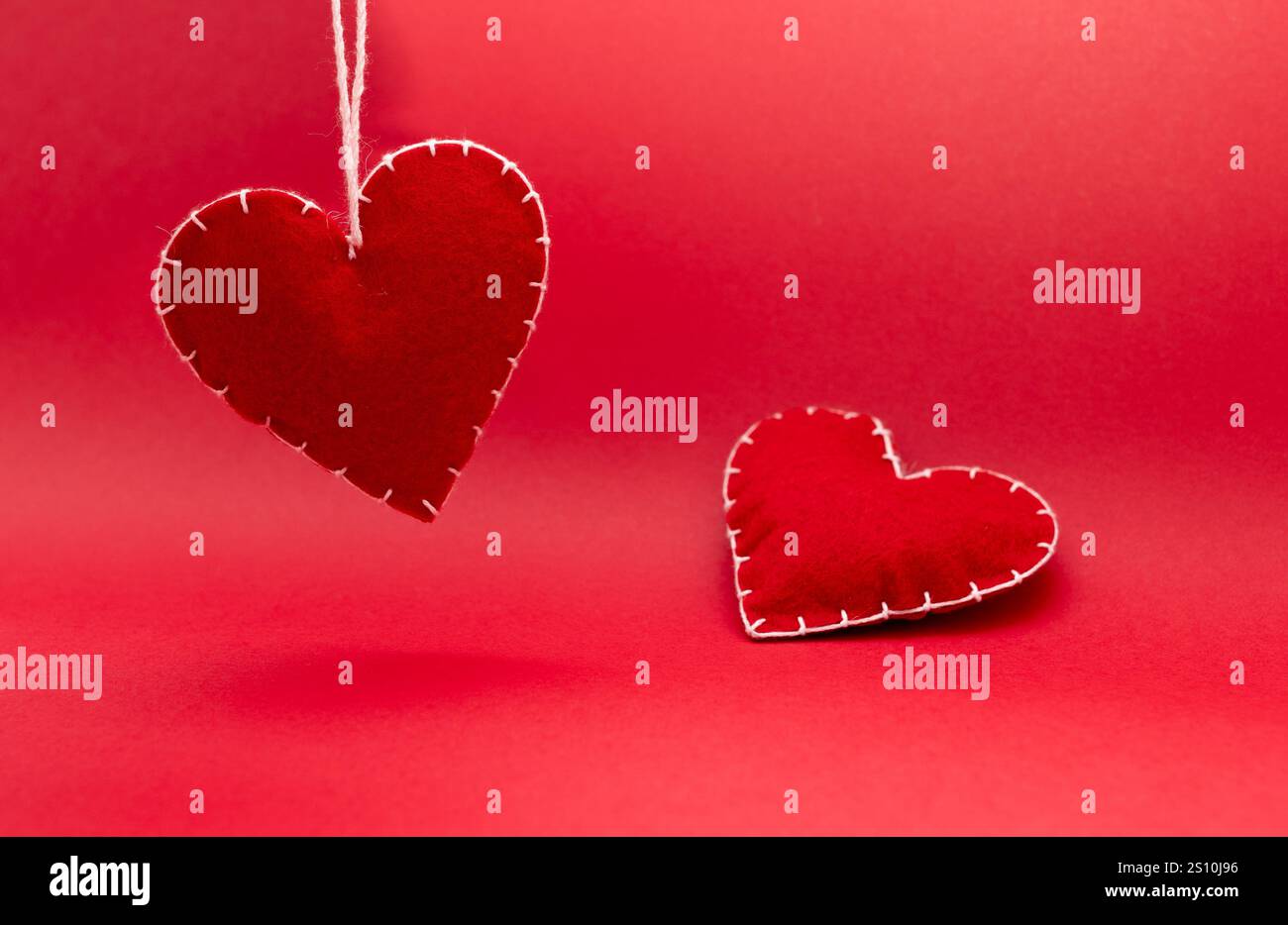 astrazione di amore e relazione, cuori rossi di lana fatti a mano su sfondo rosso, incontri e concetto di san valentino Foto Stock