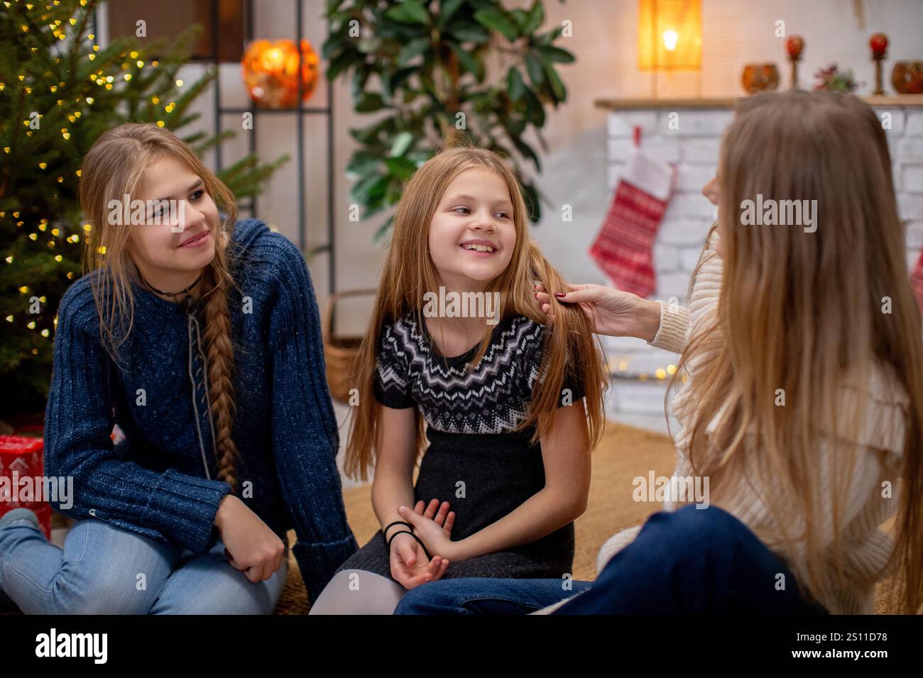 Un momento di gioia in famiglia accanto all'albero di Natale splendidamente decorato, condividendo sorrisi e amore insieme Foto Stock