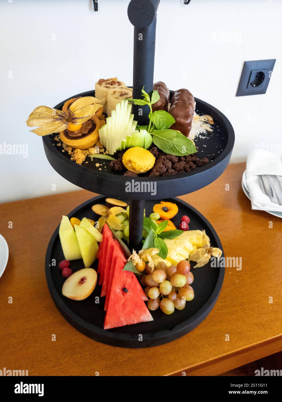 Delizioso vassoio di frutta e pasticceria, perfetto per un soggiorno di lusso in hotel o per un'occasione speciale. Foto Stock