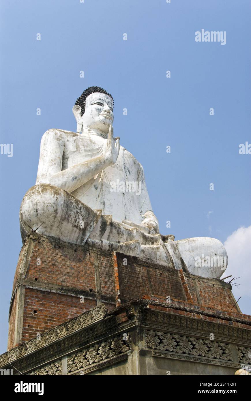 Una statua di Buddha molto grande si trova accanto a uno stagno a Wat Ek Phnom, un tempio atmosferico, parzialmente rovinato dell'XI secolo, 11 km. A nord di Battambang, Cambogia. Foto Stock