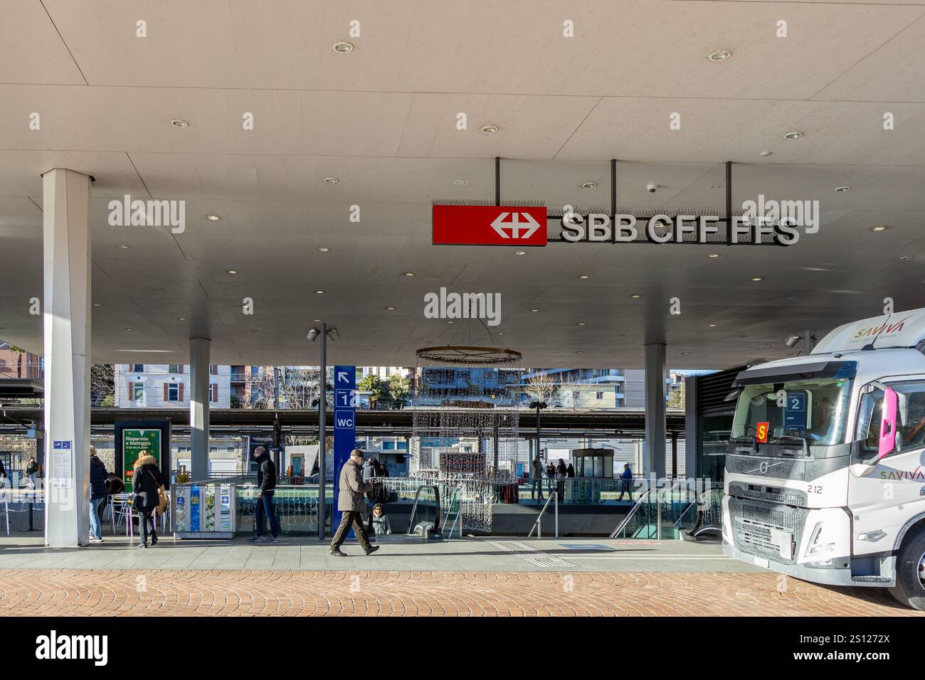 Lugano, Svizzera - 24 dicembre 2024: Ingresso della stazione ferroviaria di Lugano con i viaggiatori Foto Stock