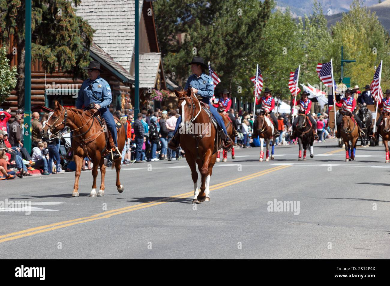 Cavalieri patriottici che tengono bandiere americane in una parata municipale pubblica, Wagon Days, Sun Valley, Idaho Foto Stock