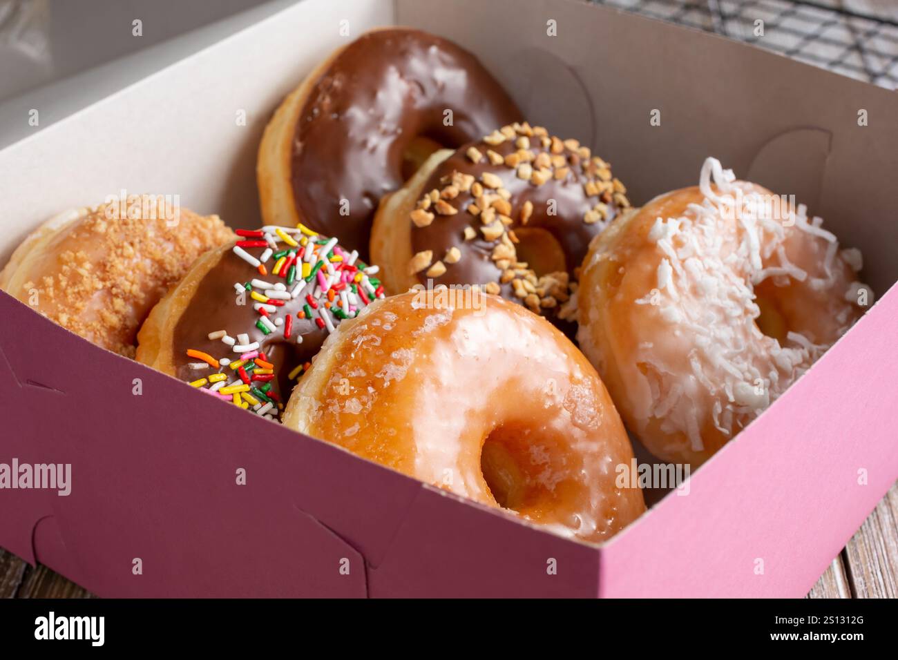 Una vista di una scatola rosa piena di una mezza dozzina di ciambelle preferite. Foto Stock