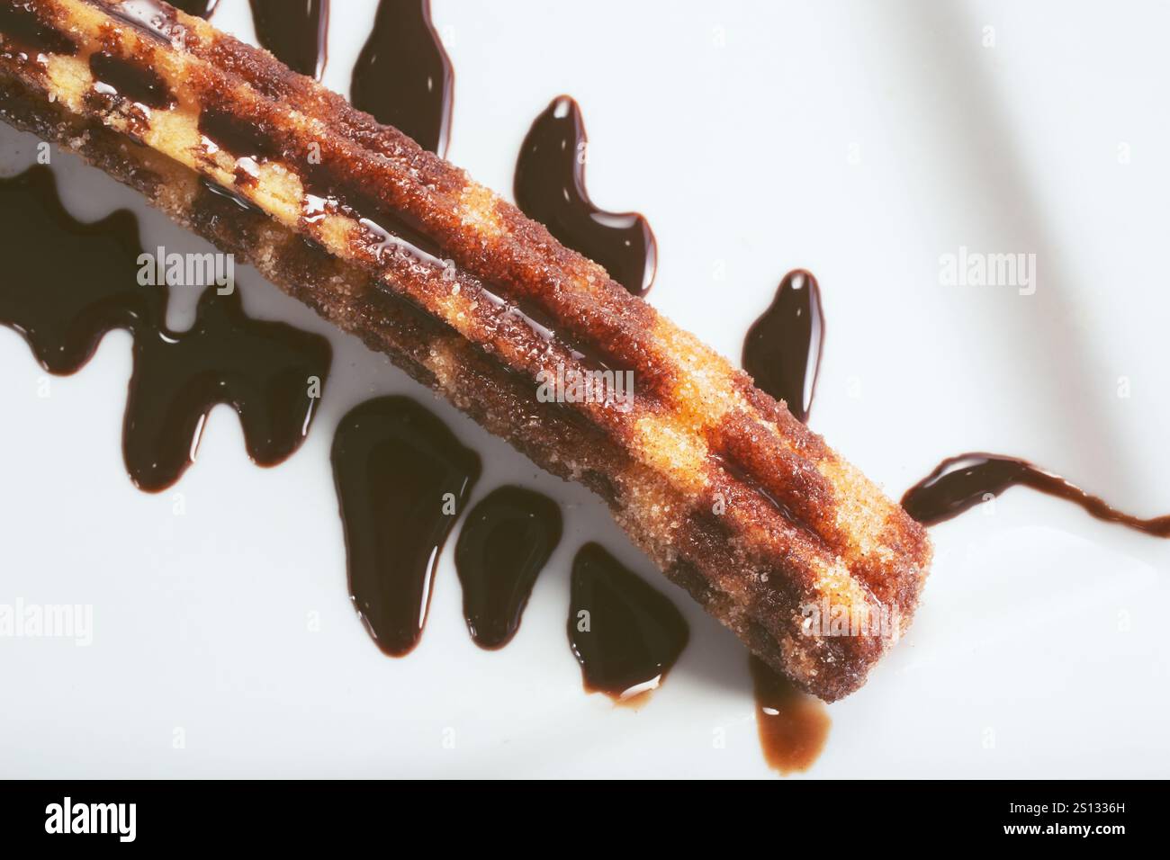 Una vista dall'alto verso il basso di un piatto di churro condito con sciroppo al cioccolato. Foto Stock