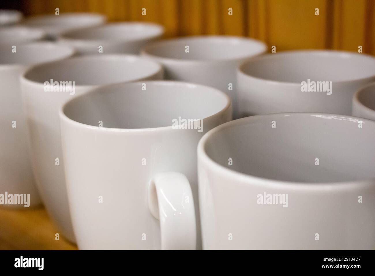 Vista ravvicinata di un ripiano della dispensa pieno di tazze da caffè in ceramica bianca. Foto Stock