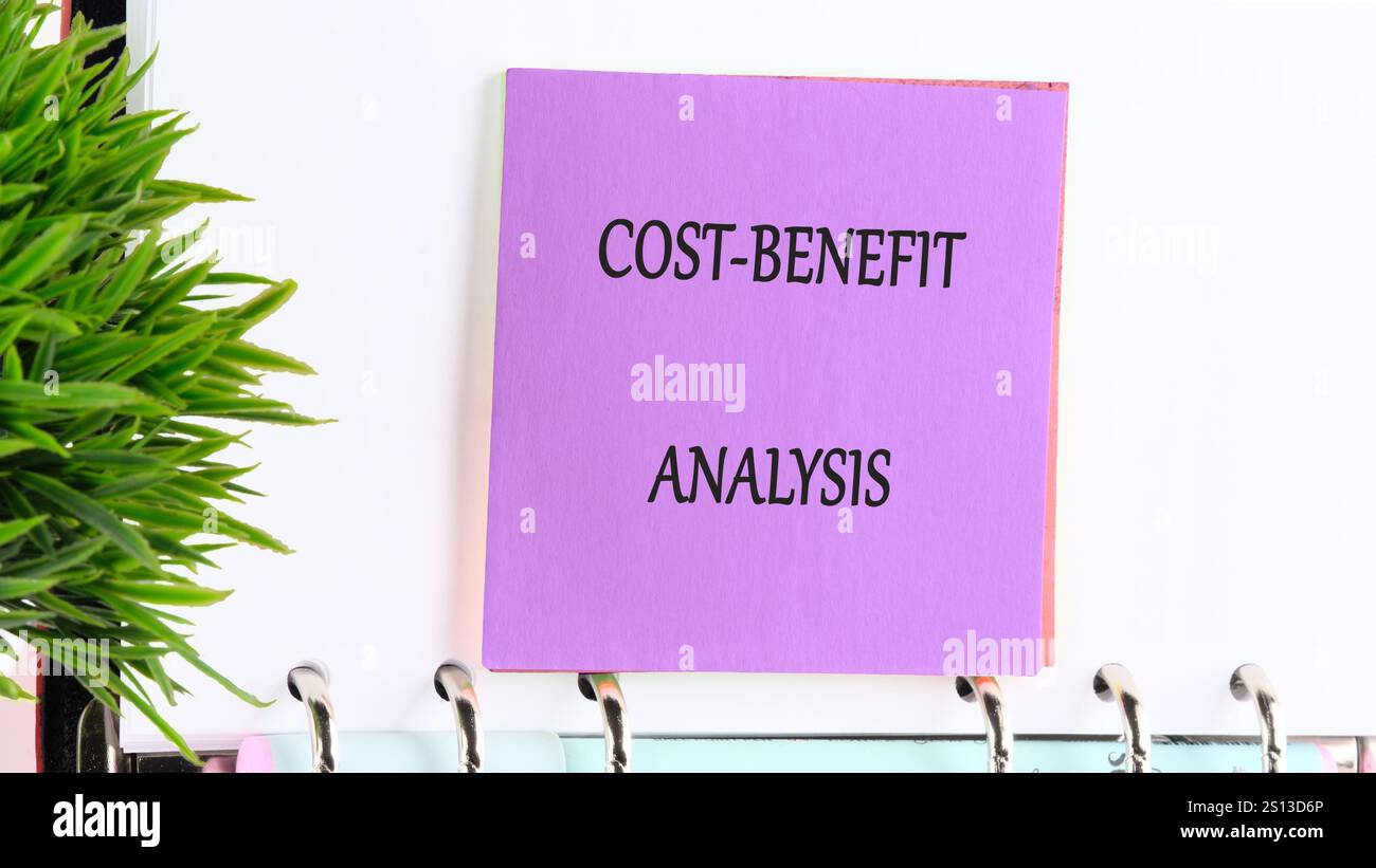 Una nota adesiva colorata etichettata con l'analisi costi-benefici viene visualizzata in modo preminente su una clipboard. Sullo sfondo, gli elementi di un ufficio moderno sono Foto Stock