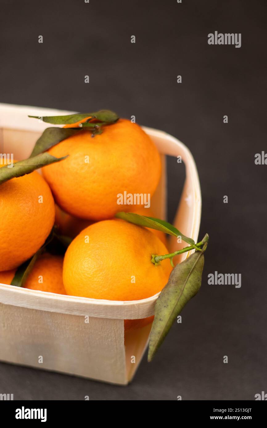 Primo piano di frutta mandarina in una scatola di legno su sfondo grigio Foto Stock